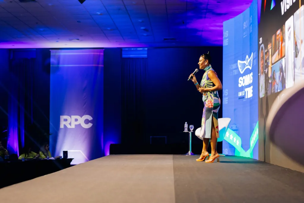 Palestrante no palco com a marca RPC ao fundo